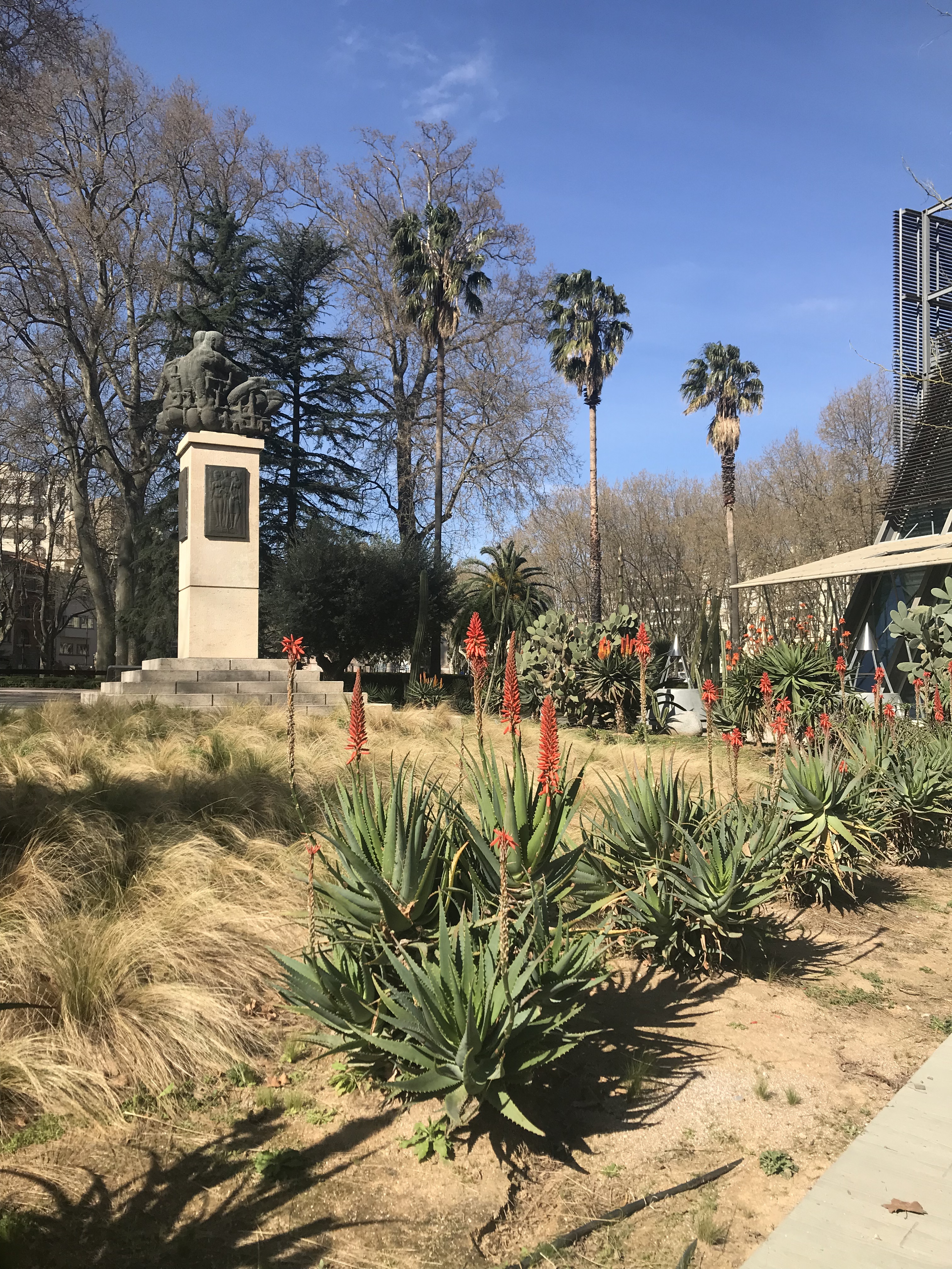 jardin public avec statue et fleurs rouges