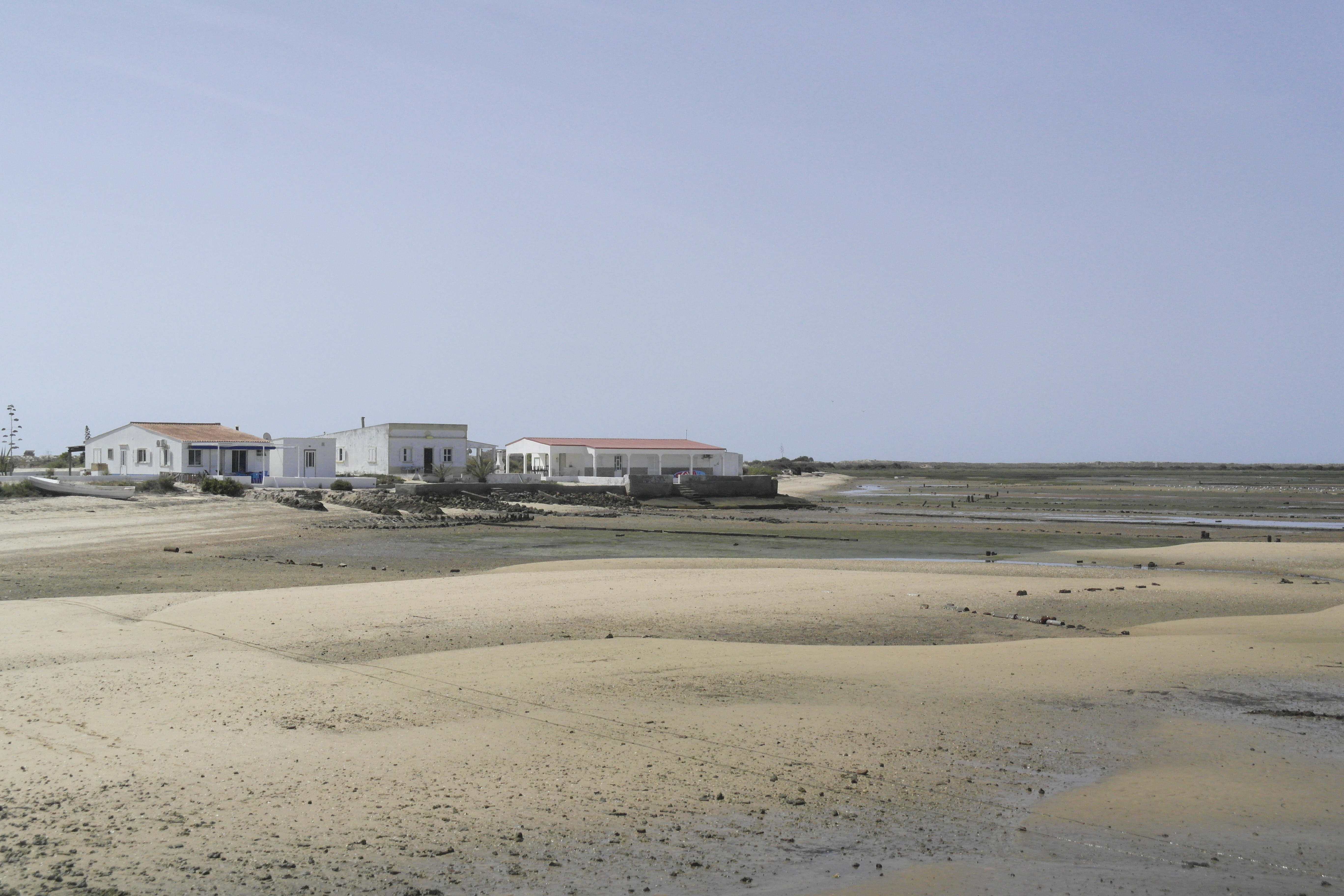 étendue de sable à marée basse, maisons blanches au fond