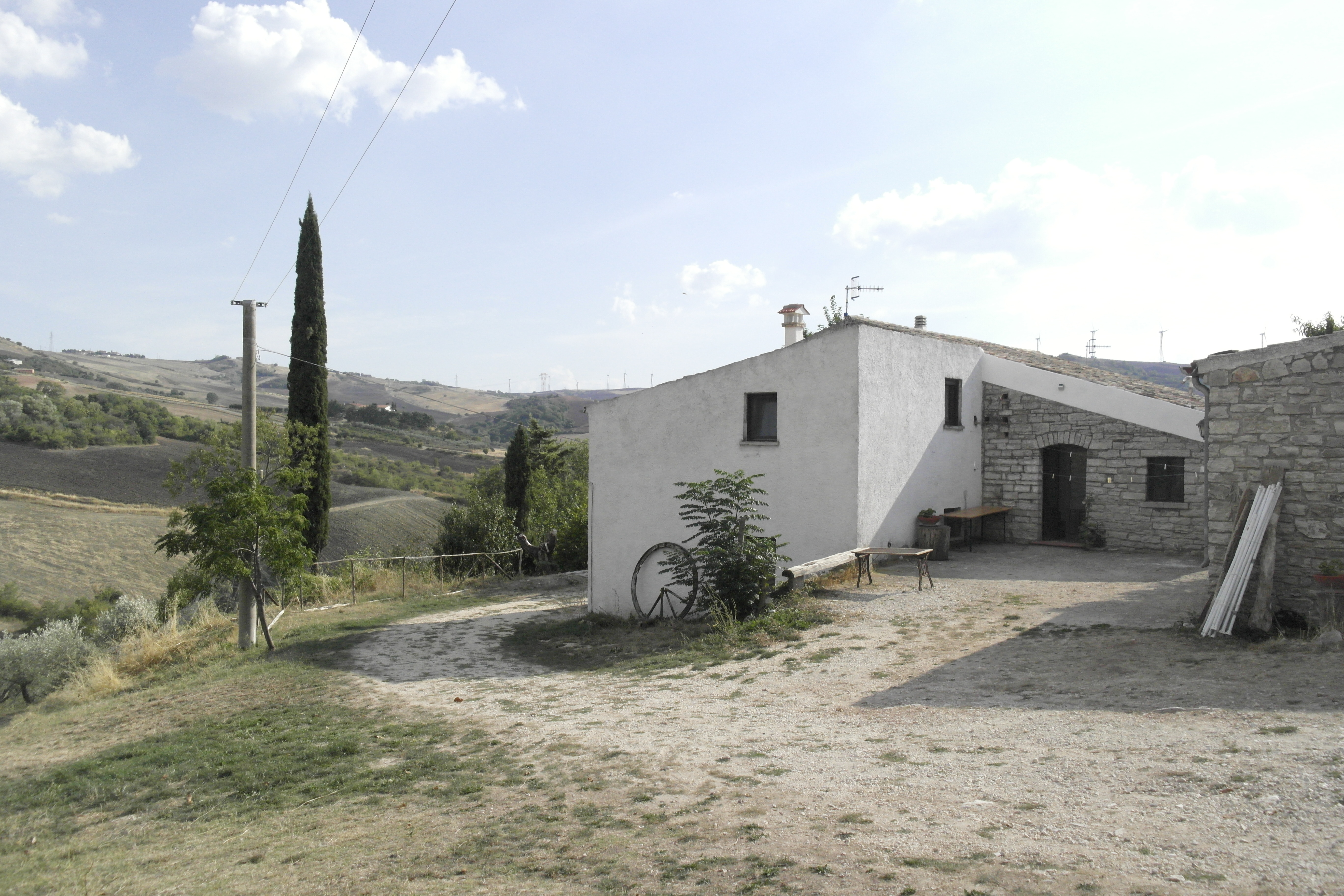 maison de campagne en pierre avec une partie enduite en blanc, paysage collinaire