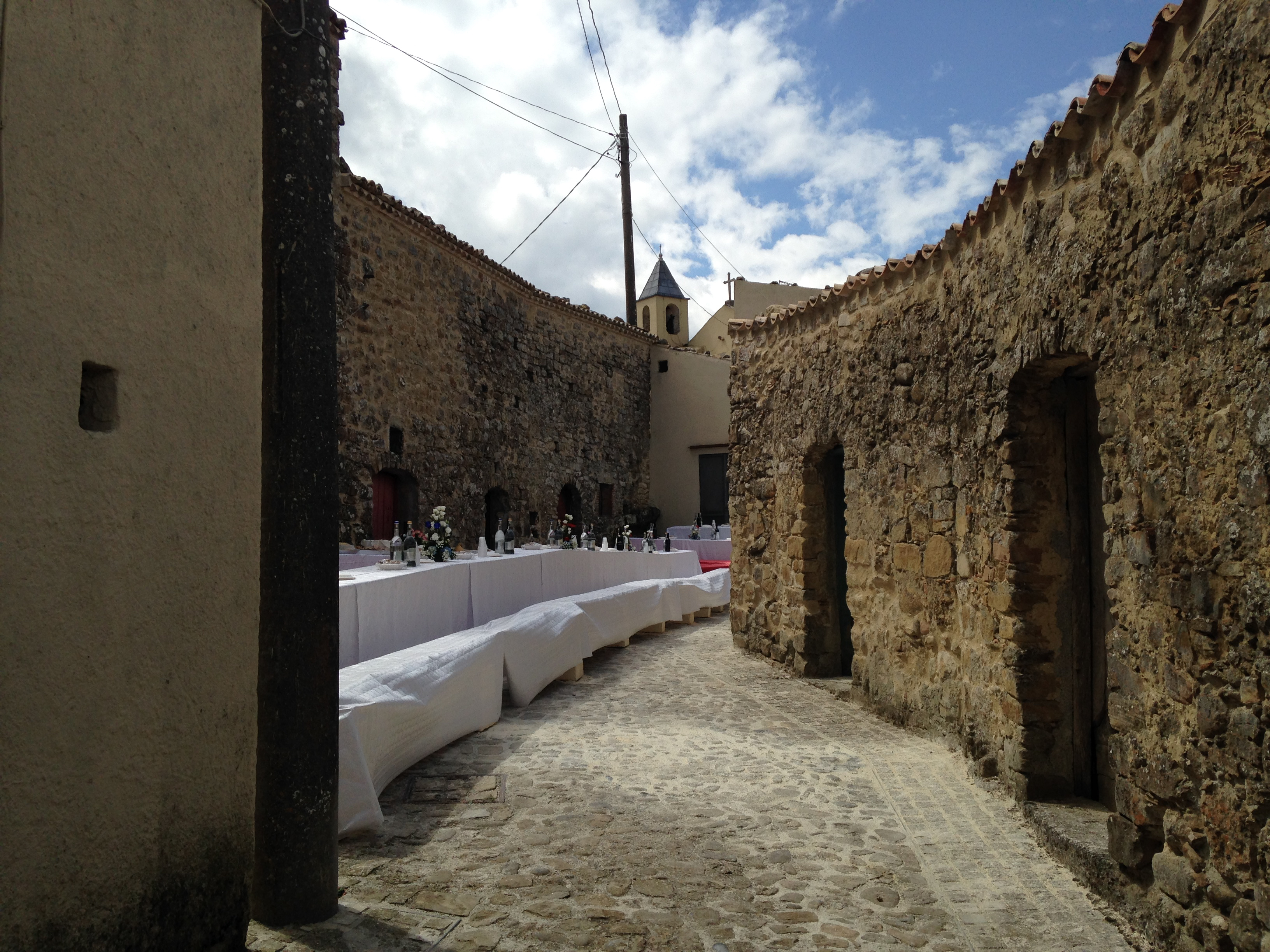 ruelle bordée de caves en pierre, tables avec nappes blanches dressées au milieu